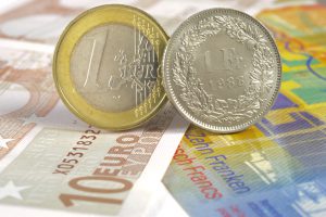 euro and swiss franc coin on banknotes